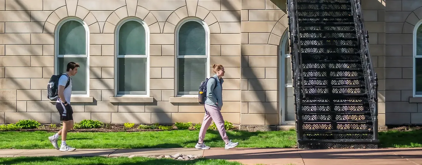 Two students walking outside of Ambrose Hall